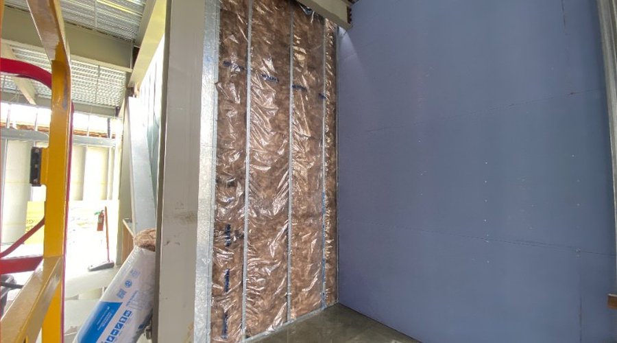 A site photograph of an interior wall cavity with exposed insulation.